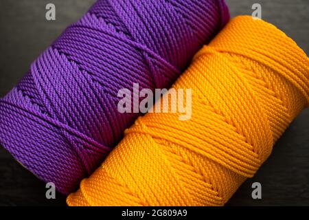 Nahaufnahme von verschiedenen bunten Fadenrollen auf einem schwarzen Holztisch Stockfoto