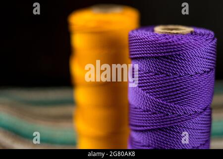 Nahaufnahme von verschiedenen bunten Fadenrollen auf einer bunt gestreiften Matte Stockfoto