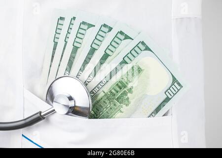 Konzept der bezahlten Medizin. Arzttasche mit Stethoskop und US-Dollar-Scheinen Stockfoto