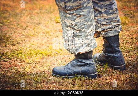 Der Mann steht in Militärstiefeln und -Hosen Stockfoto