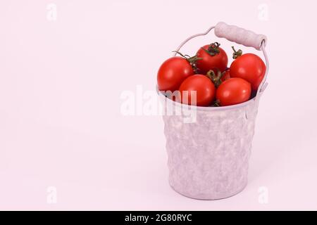 Schöne rote Tomaten in einem weißen Eimer auf weißem Hintergrund Stockfoto