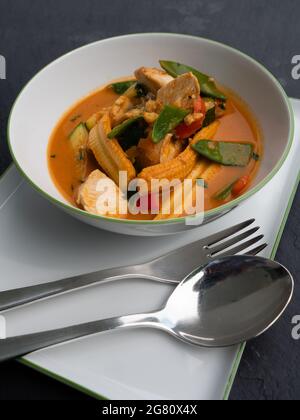 Würziger roter Thai Curry mit Huhn und Gemüse in einer Schüssel, vertikale Ausrichtung Stockfoto