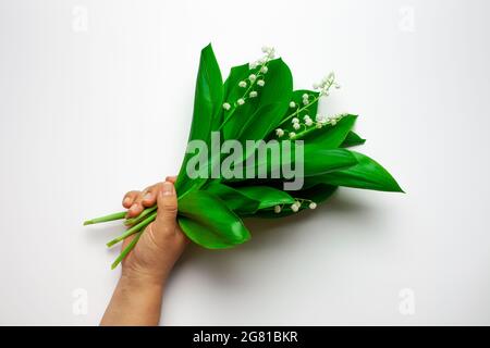 Weibliche Palme halten eine lilly of the Valley Bouquet auf dem weißen isolierten Hintergrund. Sommer- oder Muttertagskonzept Stockfoto