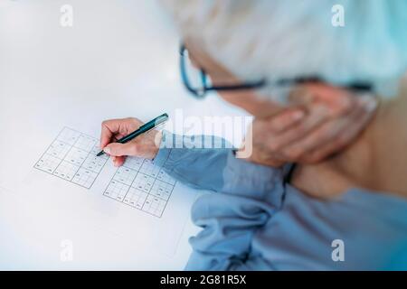 Ältere Frau löst Sudoku-Rätsel Stockfoto