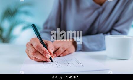 Ältere Frau löst Sudoku-Rätsel Stockfoto