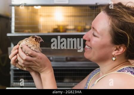 Die Farmerin hält häusliche Wachteln zärtlich in den Händen Stockfoto