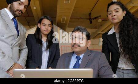 Senior Boss Manager in Südasien, der sich die Präsentation seines Junior-Teams auf dem Laptop-Monitor ansieht Stockfoto