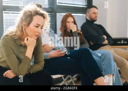 Nahaufnahme der müden jungen kaukasischen Frau, die in der Warteschlange in der modernen Bürolobby auf ein Vorstellungsgespräch wartet Stockfoto