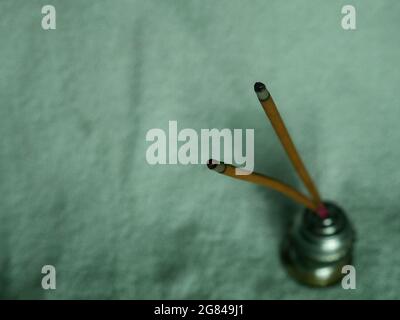 Religiöse Duftstäbchen brennen mit rotem Feuerpunkt, aufgenommen vor weißem Hintergrund. Stockfoto