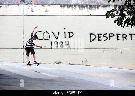 Teenage Boy Skateboarding vor Covid-19 Graffiti, Barcelona, Spanien. Stockfoto