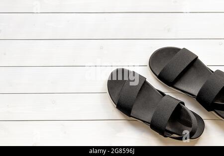 Lässige schwarze Sandalen mit offenem Zehenbereich aus recycelten Öko-Kunststofffasern für Damen auf dem weißen Holzhintergrund. Konzept der „Zero Waste“-Kleidung. Sommer Sho Stockfoto