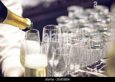 Wir gießen Wein in viele Gläser für eine Dinnerparty, mit einem schmaleren Fokus geschossen. Stockfoto