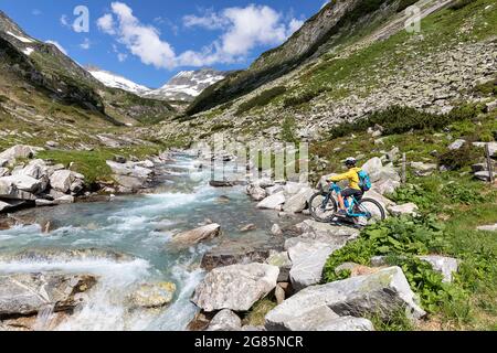 Junge auf dem Fahrrad beim Blick auf den Alpenstrom vom Gletscher im Sommer im Nationalpark hohe tauern, Österreich Stockfoto