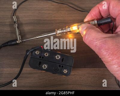 Man’s fingers connecting a low voltage Test lamp to Check a 12 Volt battery Power source. Stockfoto