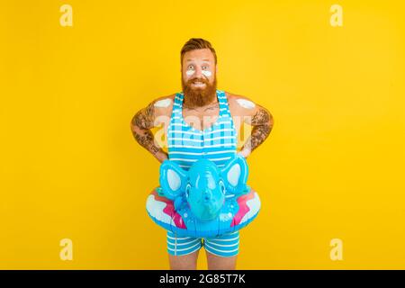 Nachdenklicher Mann mit aufblasbarem Donut und Elefant ist bereit zum Schwimmen Stockfoto