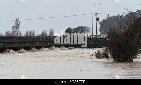 HOCHWASSER UNTER DER MOTUEKA-BRÜCKE. Motueka, Neuseeland 17. Juli 2021. Der Motueka River fließt unter der Motueka-Brücke in einem schlammigen Wildbach, nachdem sintflutartige Regenfälle in Neuseeland zu großen Überschwemmungen geführt haben. © Anne Webber / Alamy Live News Stockfoto