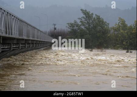 DER FLUSS MOTUEKA FLIESST UNTER DER BRÜCKE DES FLUSSES MOTUEKA. Motueka, Neuseeland 17. Juli 2021. Der Motueka River fließt unter der Motueka-Brücke in einem schlammigen Wildbach, nachdem sintflutartige Regenfälle in Neuseeland zu großen Überschwemmungen geführt haben. © Anne Webber / Alamy Live News Stockfoto