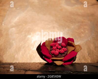 Tropische handgemachte Tonkunst Blume auf hölzerner Oberfläche auf weißem Hintergrund gehalten. Stockfoto