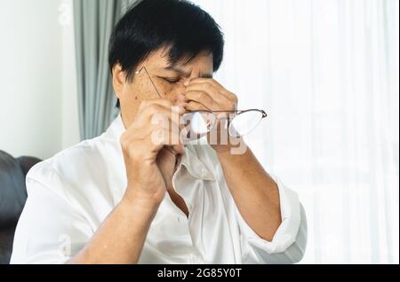 Müde alte Frau Brillen entfernen, massieren die Augen nach dem Lesen Buch aus Papier. Gefühl Beschwerden wegen der langen Brille, Augen leiden. Stockfoto