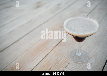 Luxuriöser Espresso martini-Cocktaildrink in elegantem Glas auf Holzhintergrund Stockfoto