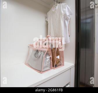 Offener weißer Schrank mit Kleidung und Taschen und leerem Platz im Schrank Stockfoto