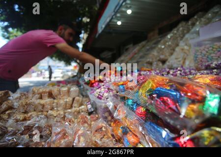 Gaza, Palästina. Juli 2021. 17. Juli 2021, Dair al Balah, der Gazastreifen, Palästina: Ein palästinensischer Verkäufer verkauft Süßigkeiten, ein Leiter von Eid al-Adha auf dem Stadtmarkt von Dair al Balah im Zentrum des Gazastreifens, Eid al-Adha, Arabisch für das Opferfest, Es ehrt die Bereitschaft von Ibrahim, seinen Sohn Ismail als einen Akt des Gehorsams gegenüber Gottes Befehl zu opfern, Gott stellte ein Lamm zum Opfer statt Ismail. (Bild: © Mahmoud Khattab/Quds Net News via ZUMA Press Wire) Bild: ZUMA Press, Inc./Alamy Live News Stockfoto