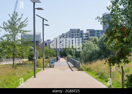 Ein Gang im Queen Elizabeth Olympic Park in Stratford an einem sonnigen Tag mit Wohnhäusern in der Ferne. London - 17. Juli 2021 Stockfoto