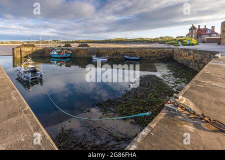 Ein schöner, stiller Morgen mit den Fischerbooten, der sich im Hafen von Beadnell an der Küste von Northumberland, England, widerspiegelt. Stockfoto