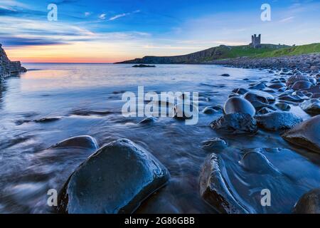 Dunstanburgh Castle bei Sonnenaufgang von Embleton Bay an der Northumberland-Küste, England, Großbritannien Stockfoto