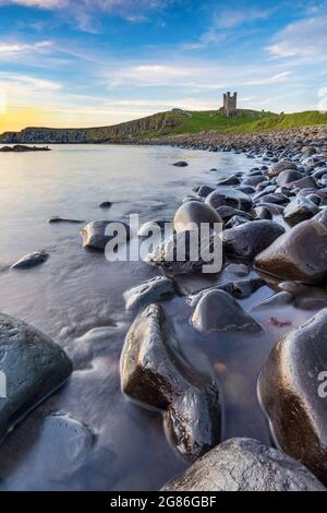 Dunstanburgh Castle bei Sonnenaufgang von Embleton Bay an der Northumberland-Küste, England, Großbritannien Stockfoto