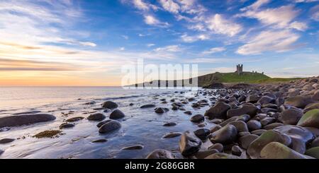 Dunstanburgh Castle bei Sonnenaufgang von Embleton Bay an der Northumberland-Küste, England, Großbritannien Stockfoto