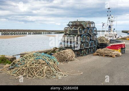 Hummertöpfe und -Seil lagen am Hafen von Amble in Northumberland, England. Stockfoto