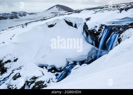 Ein Gletscherfluss bahnt sich seinen Weg durch Schnee und Eis auf der Snaefellsnes Penninsular in Westisland Stockfoto