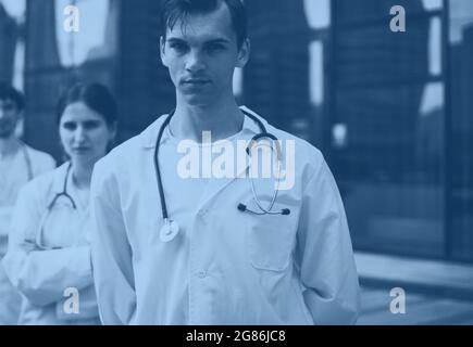 Gruppe von ernsthaften jungen Ärzten, die vor dem Krankenhaus stehen. Stockfoto