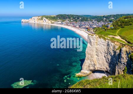 Der Strand von Etretat in der Normandie, eine beliebte französische Küstenstadt, die an einem sonnigen Tag für ihre Kreidefelsen wie die Amont-Klippe in der Ferne bekannt ist. Stockfoto