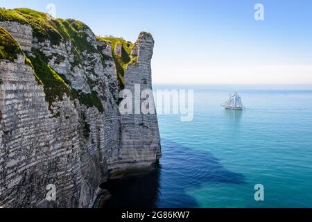 Ein weißes Segelschiff fährt an einem sonnigen Tag in voller See vor der Aval-Klippe in Etretat, Normandie. Stockfoto