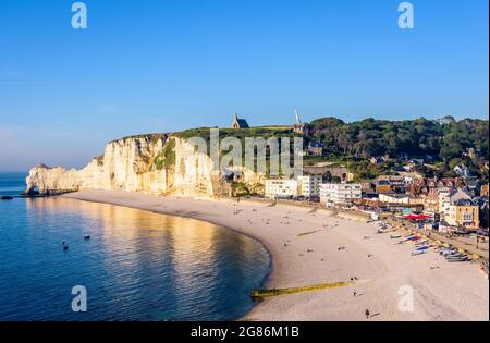 Der Strand von Etretat in der Normandie, eine beliebte Küstenstadt, die für ihre Kreidefelsen bekannt ist, mit der Kapelle Notre-Dame de la Garde mit Blick auf die Klippe von Amont. Stockfoto