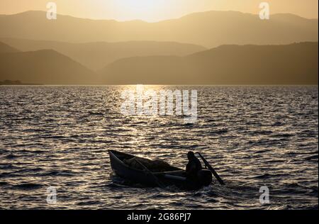 Ein Fischer bei Sonnenuntergang am Mikri Prespa See im Dorf Mikrolimni in Mazedonien, Nordgriechenland. Stockfoto