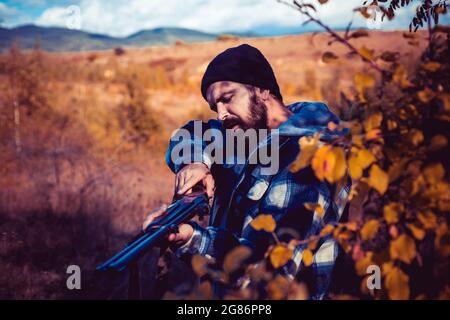 Jäger mit Schrotflinte auf der Jagd. Herbstjagd. Jagdsaison geschlossen und geöffnet. Wilderer im Wald. Bergjagd. Stockfoto