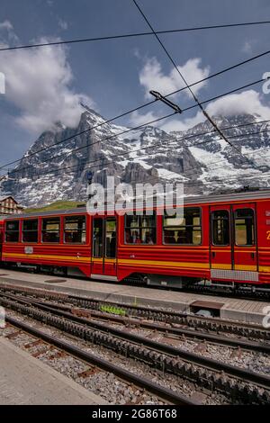 Jungfraubahn Iconic Red Train in kleine Scheidegg mit Schweizer Alpen Eiger Mountains im Hintergrund - Jungfrau Region, Schweiz Stockfoto