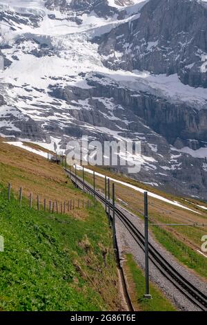 Jungfraubahn Iconic Red Train in kleine Scheidegg mit Schweizer Alpen Eiger Mountains im Hintergrund - Jungfrau Region, Schweiz Stockfoto