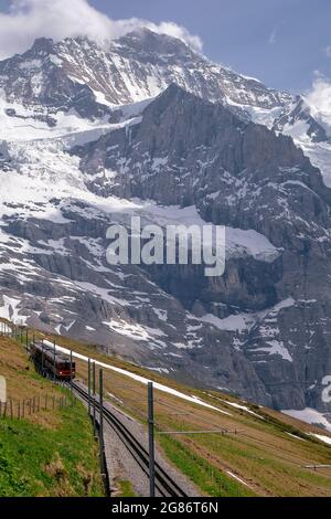 Jungfraubahn Iconic Red Train in kleine Scheidegg mit Schweizer Alpen Eiger Mountains im Hintergrund - Jungfrau Region, Schweiz Stockfoto