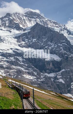 Jungfraubahn Iconic Red Train in kleine Scheidegg mit Schweizer Alpen Eiger Mountains im Hintergrund - Jungfrau Region, Schweiz Stockfoto