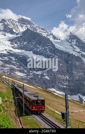 Jungfraubahn Iconic Red Train in kleine Scheidegg mit Schweizer Alpen Eiger Mountains im Hintergrund - Jungfrau Region, Schweiz Stockfoto