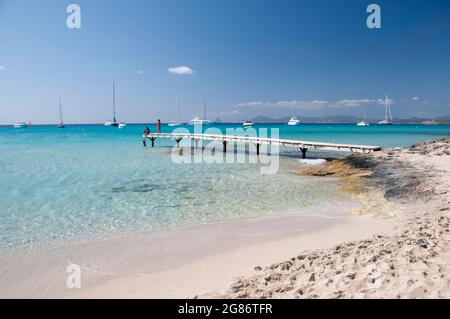 Ein paar Touristen beobachten den Horizont über dem Mittelmeer von einem hölzernen Pier an einem Strand in Formentera, Spanien Stockfoto