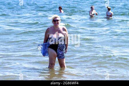 Dundee, Tayside, Schottland, Großbritannien. Juli 2021. UK Wetter: Juli Hitzewelle fegt über Nordostschottland mit Höchsttemperatur 27 Grad Strandbesucher machen einen Tag am Broughty Ferry Beach in Dundee. Eine ältere Frau aus der Region genießt die warme Sommersonne, die sich im Fluss Tay abkühlt. Kredit: Dundee Photographics/Alamy Live Nachrichten Stockfoto