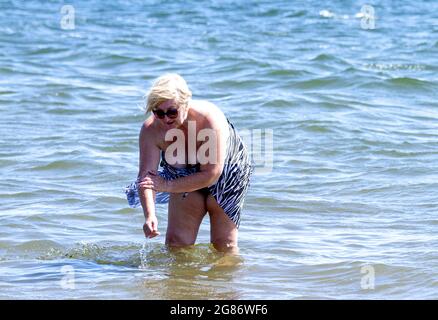 Dundee, Tayside, Schottland, Großbritannien. Juli 2021. UK Wetter: Juli Hitzewelle fegt über Nordostschottland mit Höchsttemperatur 27 Grad Strandbesucher machen einen Tag am Broughty Ferry Beach in Dundee. Eine ältere Frau aus der Region genießt die warme Sommersonne, die sich im Fluss Tay abkühlt. Kredit: Dundee Photographics/Alamy Live Nachrichten Stockfoto