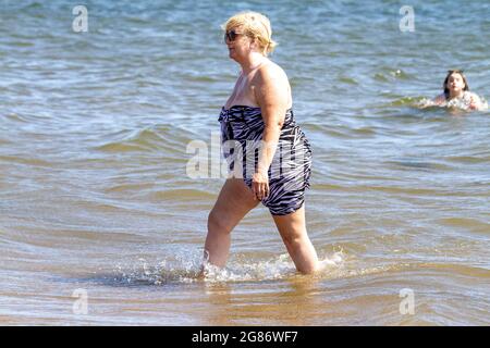 Dundee, Tayside, Schottland, Großbritannien. Juli 2021. UK Wetter: Juli Hitzewelle fegt über Nordostschottland mit Höchsttemperatur 27 Grad Strandbesucher machen einen Tag am Broughty Ferry Beach in Dundee. Eine ältere Frau aus der Region genießt die warme Sommersonne, die sich im Fluss Tay abkühlt. Kredit: Dundee Photographics/Alamy Live Nachrichten Stockfoto