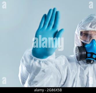 Ein Mann in einem Biohazard-Anzug macht ein Stoppschild. Stockfoto