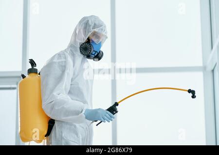 Mann in einem bakteriologischen Schutzanzug, der im Büro steht. Stockfoto